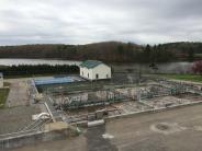 Multiple sedimentation basins in the foreground begin the biological breakdown of wastewater solids. The yellow building in the 